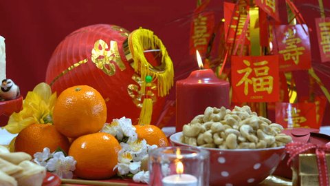 Chinese New Year party table in red and gold theme with food and traditional decorations, closeup dolly pan.