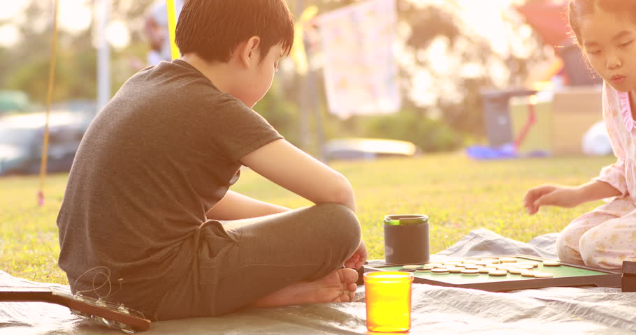 Happy asian boy and girl playing board game in camping area