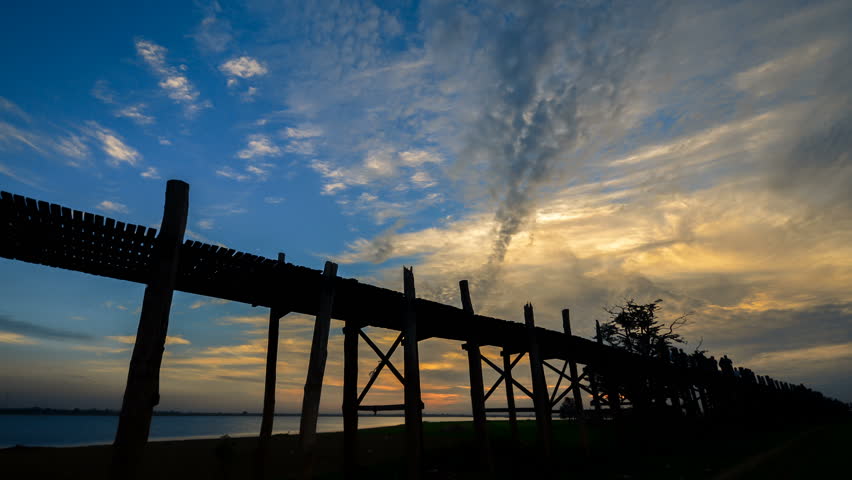 U Bein bridge in Myanmar silhouettes of people timelapse at sunset. U Bein is the longest wooden bridge. Zoom in timelapse. 