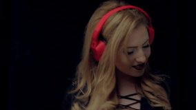 Smiling young woman with red lipstick listening to music on blu dancing