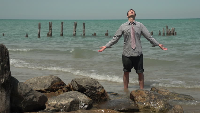 Business man standing in the ocean enjoying the sun
