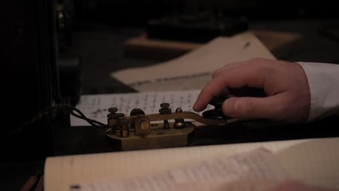 VIRGINIA - SUMMER 2016 - Reenactment, Recreation, historical old telegraph operator with radio machinery and using morse code, taps a message.  Listens to message.  Circa 1890-1920s.  Titanic wireless