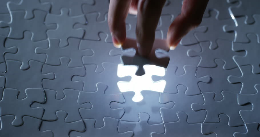 A creative completes the black or white light puzzle putting the last missing piece. Concept: cooperation, teamwork, creativity, and access solution.