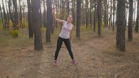 Slow motion footage of young woman stretching body before training at forest