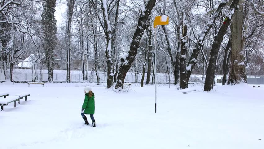 Girl throw snowball to basketball hoop. Snow play games in winter.