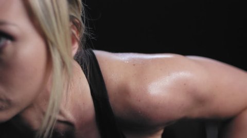 Close up profile shot of an athletic caucasian woman doing push ups on a dark background