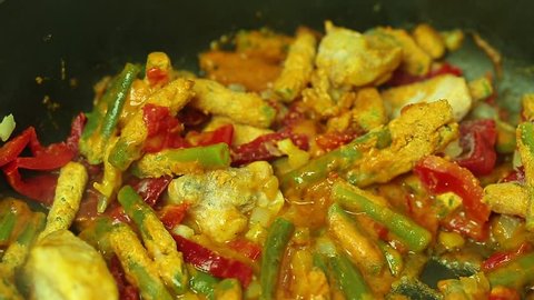 Georgian dish chakhokhbili with beans cooking in a pan closeup. Traditional spicy flavor