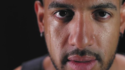 Close up shot of a muscular black man wiping the sweat off his forehead on a dark background