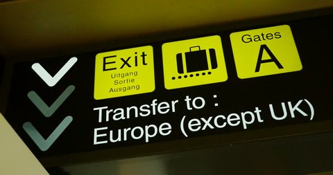 Detail of Airport sign with instruction direction toward Exit (Uitgang, Sortie, Ausagang), luggage claim, gates A and text Transfer to Europe with exception of the UK (Brexit concept)