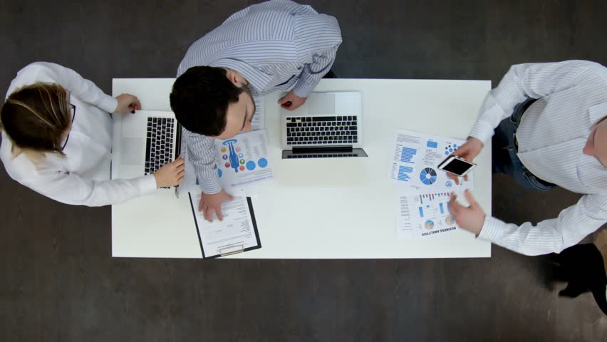 Ofice workers discussing business diagrams and wokring on laptops