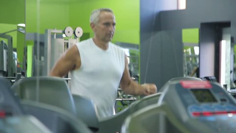 Old man runs on a treadmill