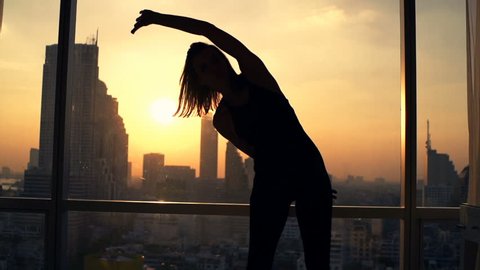 Silhouette of woman exercising bend by window during sunset at home, super slow motion 240fps
