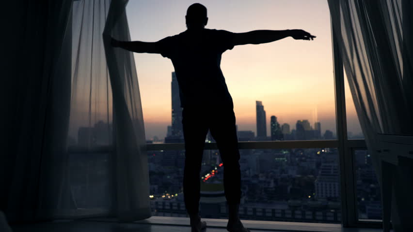 Silhouette of man unveil curtain and admire view from window during sunset
 | Shutterstock HD Video #23284552