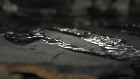 Clear water flow on the surface of the stone. Super slow motion close up