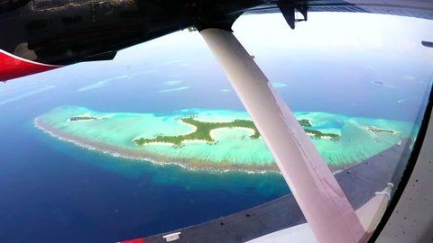 Engine of an otter twing water plane in action while flying above the maldives, showing amazing tiny colorful islands and unique turquoise color of the indian ocean. 