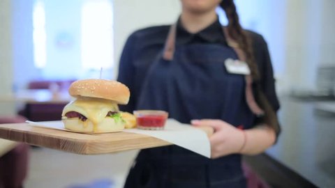 Girl waiter carries a burger.