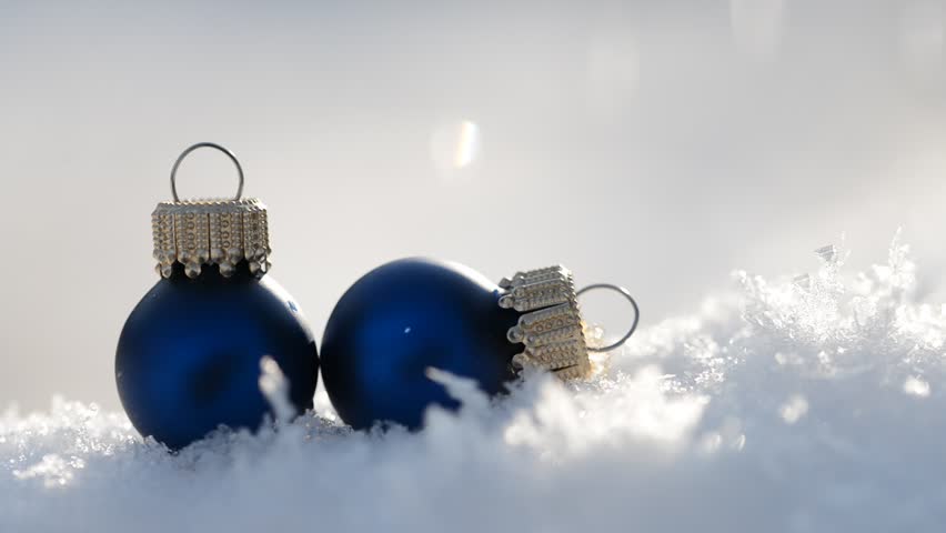 Falling snow on two blue Christmas decoration.