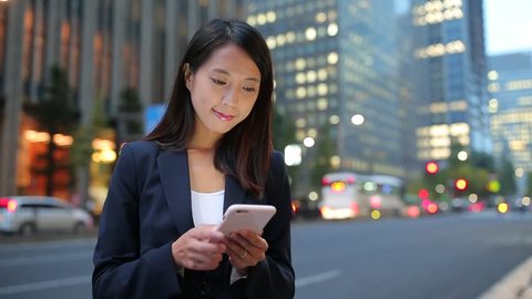 Businesswoman touching on cellphone at street