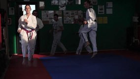 Slow motion video of an adult taekwondo training session in the gym, warming up, selective focus

