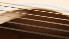 Plucked instrument body details shallow DOF 4K 2160p 30fps UltraHD panning footage - Wooden acoustic guitar E string vibration slow pan 3840X2160 UHD video