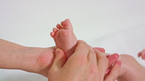 mother massaging little baby's feet with oil