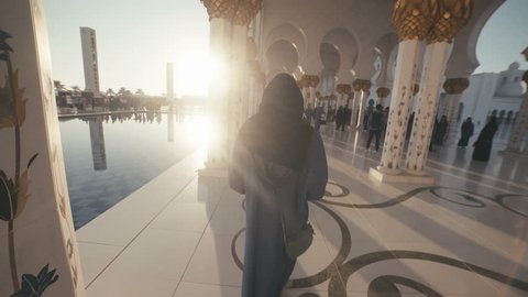 UAE, 2017: Sheikh zayed grand mosque. Mosque in Abu Dhabi. A young woman of European appearance in the traditional dress of Muslim women - black Abai - walking inside the mosque.