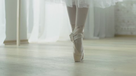 Close-up Shot of Ballerina's Legs. She Dances on Her Pointe Ballet Shoes. She's Wearing White Tutu Dress. Shot in a Bright and Sunny Studio. In Slow Motion.Shot on RED EPIC-W 8K Helium Cinema Camera.