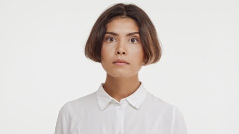 Young beautiful brunette east asian female in shirt screaming wow in surprise on white background