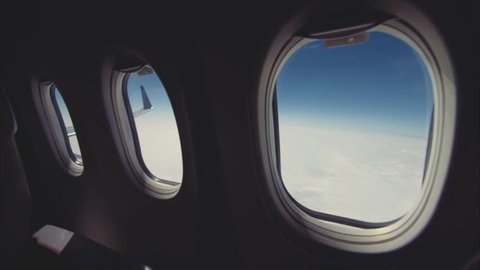 In-Flight shot. Slide camera, clouds and sky as seen through windows of an aircraft. 
