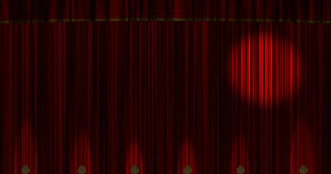 A spotlight moves across theater or stage curtains. Shell footlights up-light the bottom of the red curtains.