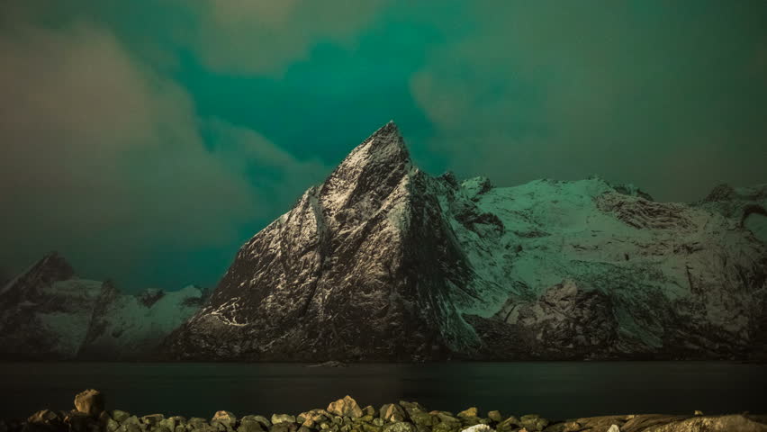 Northern lights (Aurora Borealis) on background of snowy mountains in Norway, Lofoten Islands, time lapse