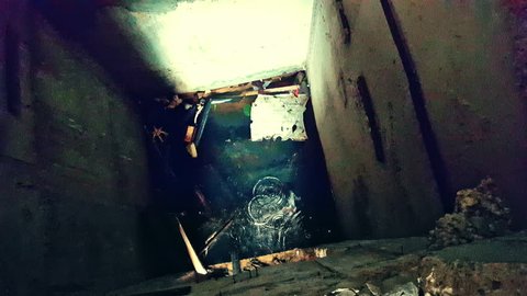 Camera comes close to flooded elevator shaft and looks down at water, dripping drops and debris. Post-apocalyptic ruins. Found footage horror movie scene. First-person perspective, live cam view.
