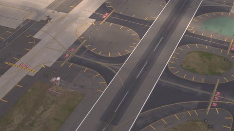 AERIAL, CLOSE UP: Flying close above large asphalt and concrete piste on big modern international airport near busy turnpike highway. Runway designator markings, numbering and signs on the track