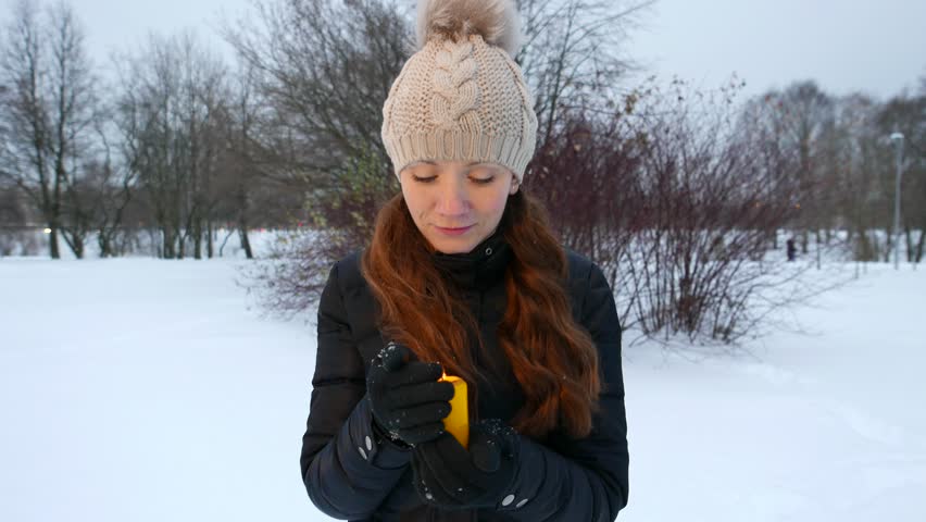 Young woman fail in try to protect burning candle, hide it from wind by hand. Fire loss by air gust, confused girl hold extinguished candle with confused face. Romantic Christmas tradition