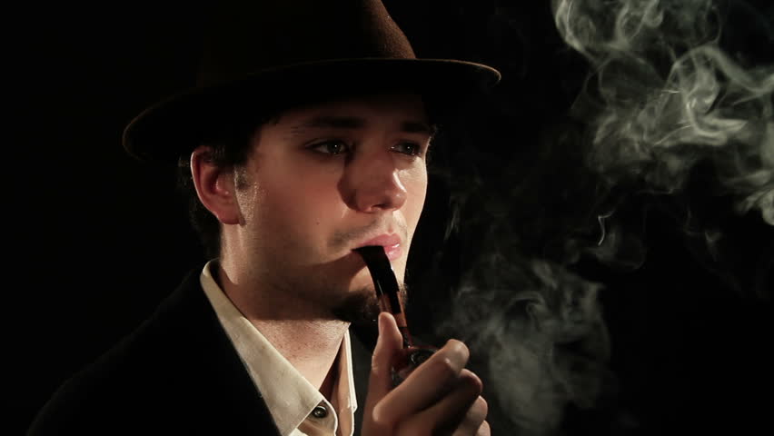 A young man smoking a pipe on a black background