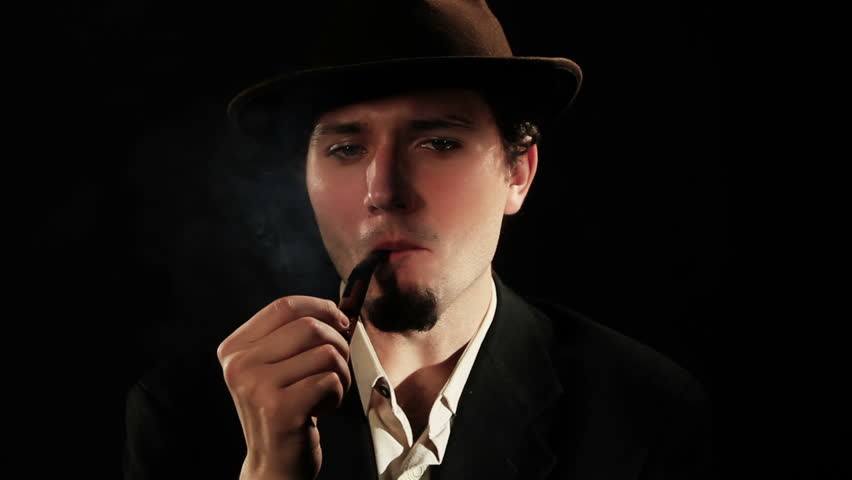 A young man smoking a pipe on a black background
