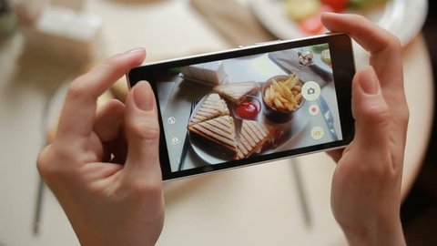 Trendy man in a restaurant make photo of food with mobile phone camera. sandwich