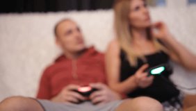 Blurring background. People with a controller in hands playing video game console.