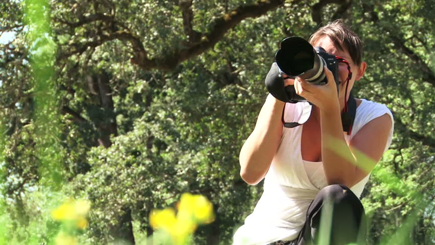 Woman photographer takes pictures outdoors.