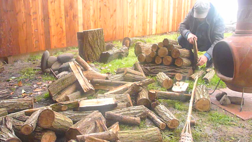 Time lapse of man stacking wood pile outdoors by fire pit.