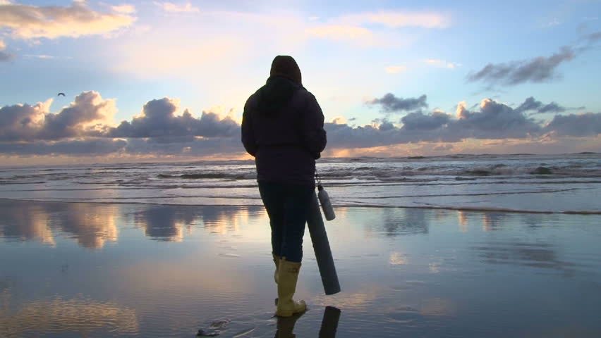 Woman with clamming gun walks Pacific Ocean in search for razor clams.