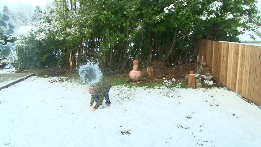 Man in winter clothes runs out to backyard after snowfall and throws snowballs