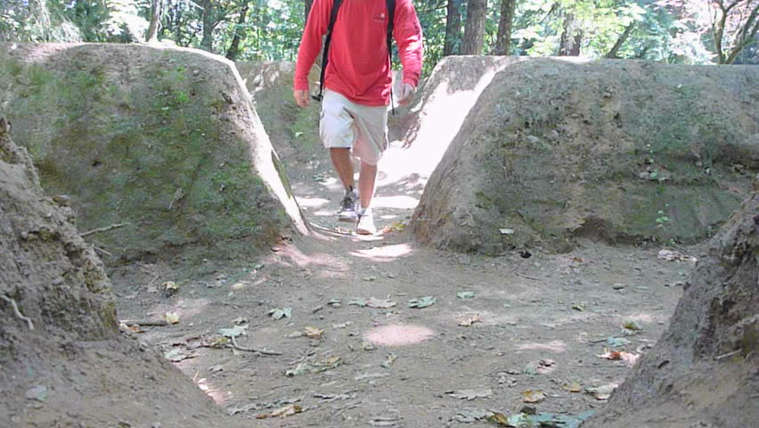 Man hikes toward, up path through dirt ruins in Oregon.