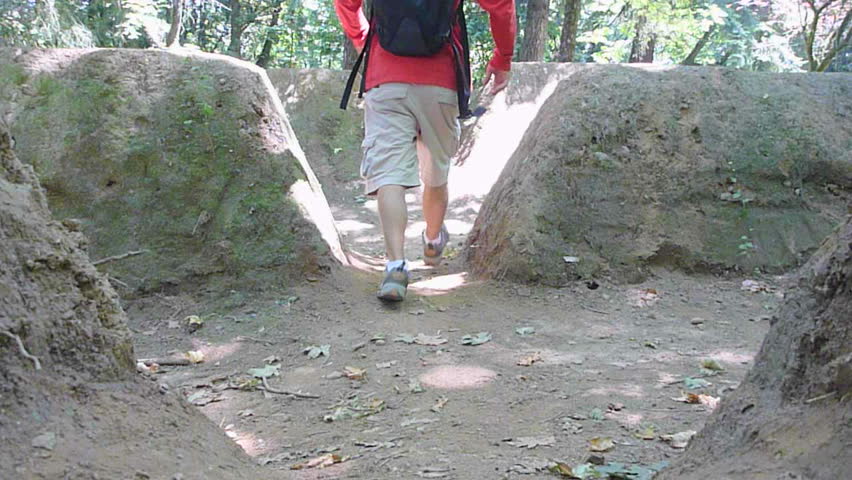 Man hikes away, down path through dirt ruins in Oregon.