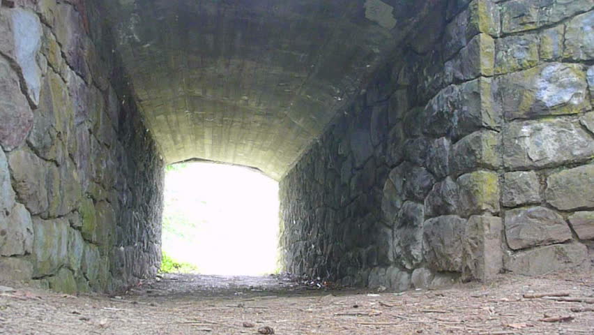 Man hikes away, down path through old tunnel in Oregon.
