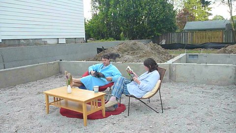 Man and woman couple set up living room furniture and have coffee in robes on new construction.