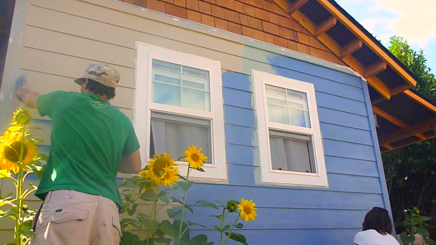 Man and woman couple paint new construction in the summer, time lapse.