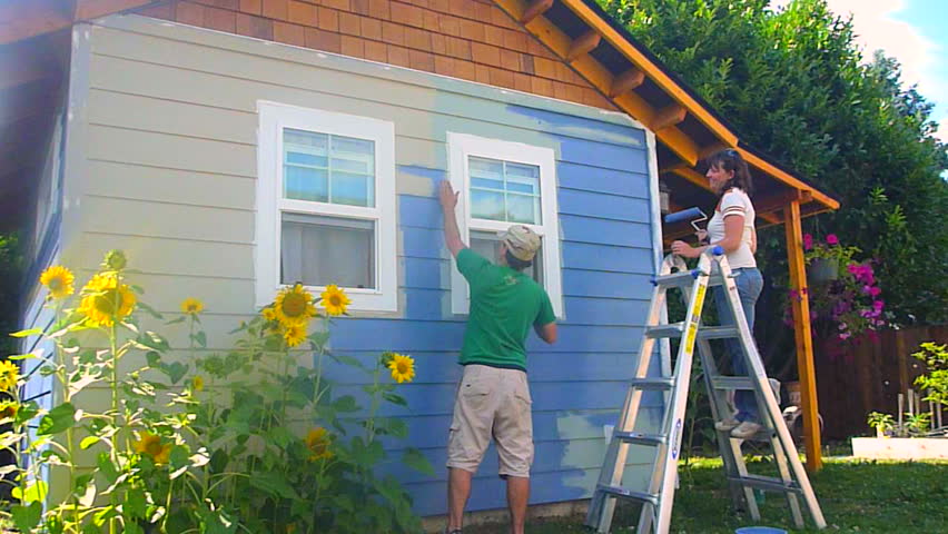 Man and woman couple paint new construction in the summer, time lapse series.