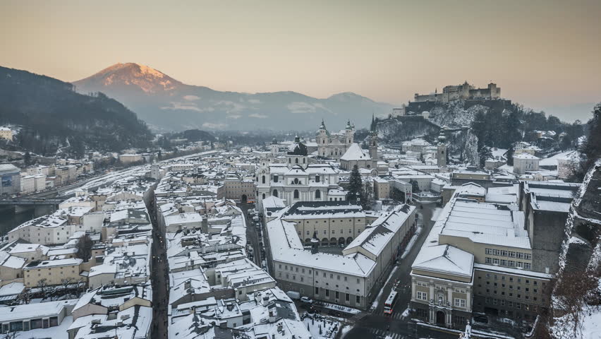 Day to night time-lapse footage of the historic city of Salzburg with famous Festung Hohensalzburg and Salzach river illuminated in beautiful twilight during scenic Christmas time in winter, Austria.