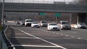 Slow motion - Commuter rush hour car traffic travels on the Long Island Expressway day time. Interstate from New York City to hamptons beaches. Vehicle roadway safety with dense population of drivers